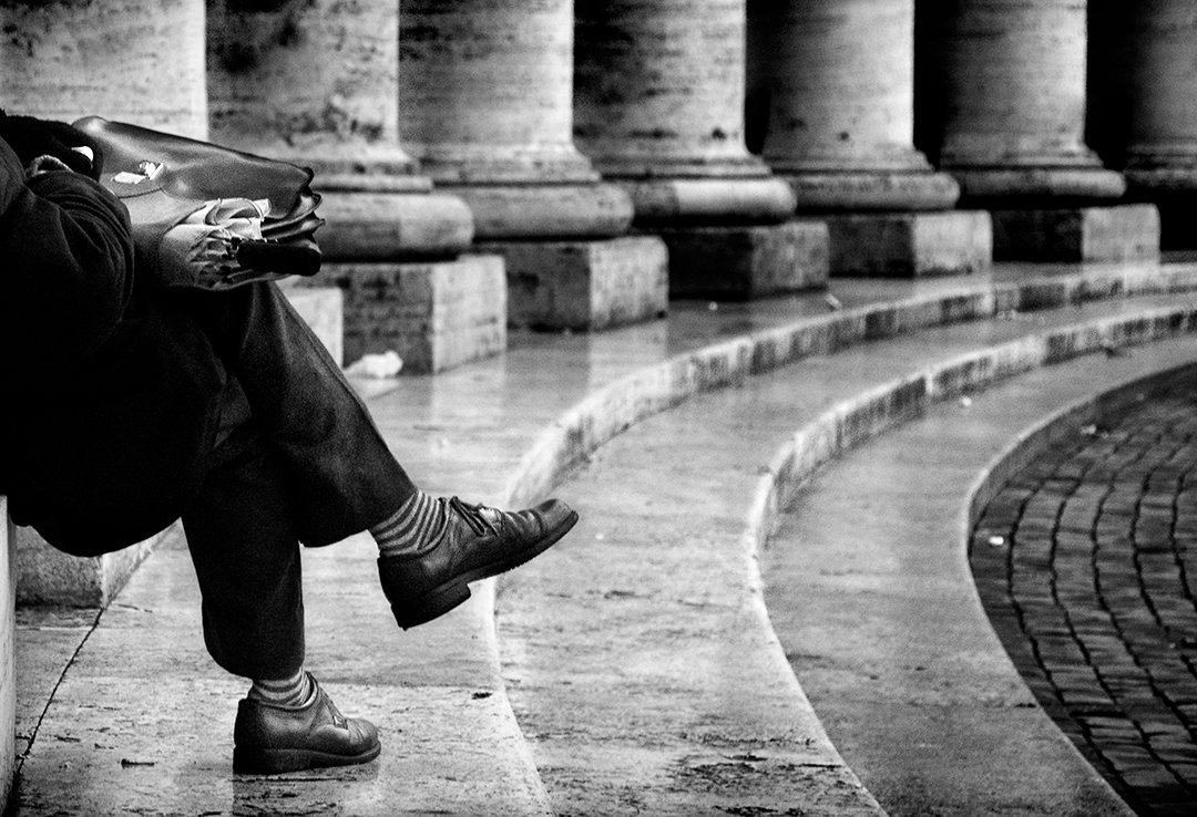 The legs of a seated person beside curved steps.